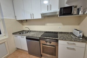 A compact kitchen with white cabinets, a dishwasher, an oven, a microwave, and a toaster. - 648B2 Apartamento Mareval (Oviedo)