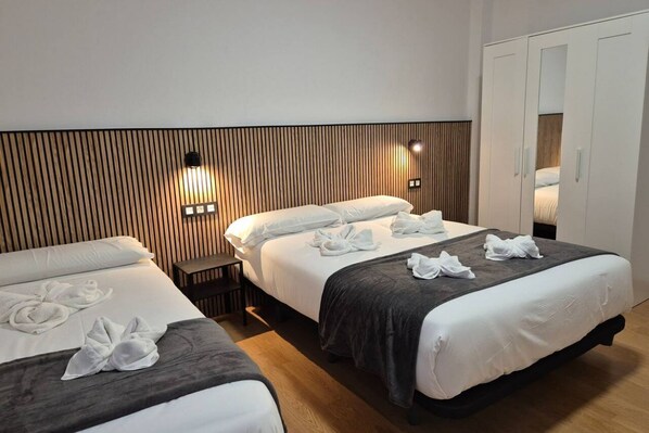 Habitación de hotel con dos camas, un armario y una mesita.