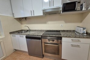 A kitchen with a dishwasher, oven, microwave, and toaster.