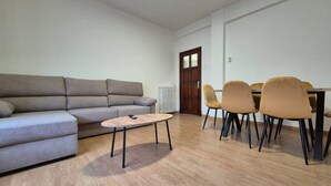 Ein Wohnzimmer mit einer Couch, einem Couchtisch und einem Essbereich mit Stühlen und Tisch.