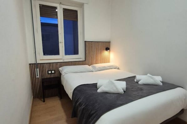 A single bed with a dark headboard, white bedding, and two towels on the bed.