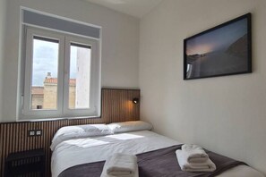 A hotel room with a bed, a window, a wall-mounted picture, and a radiator. - 648C1 Apartamento Mareval (Oviedo)