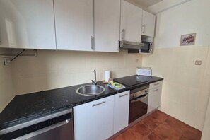 A compact kitchen with a dishwasher, a sink, a microwave, and a toaster. - 648C1 Apartamento Mareval (Oviedo)