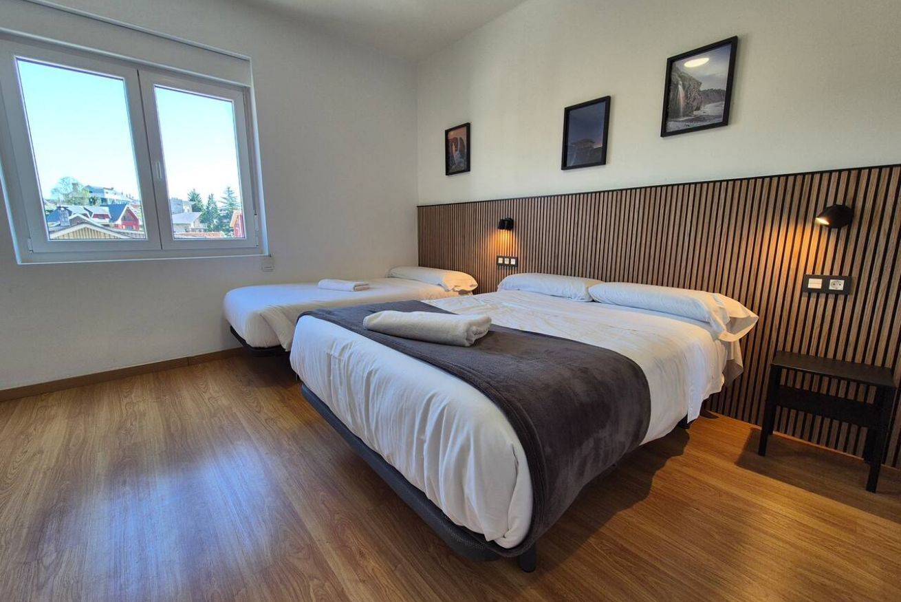 Een hotelkamer met twee bedden, een groot raam, houten wandbekleding en ingelijste foto's.
