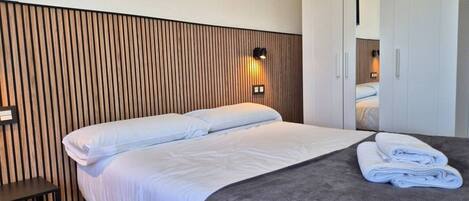 Una habitación de hotel con cama, cabecera de madera, luz de pared y armario.