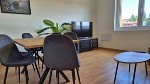A dining area with a wooden table, four chairs, a television, and a potted plant.