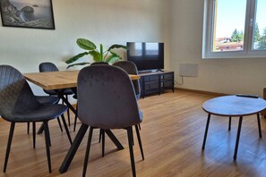 A dining area with a wooden table, four chairs, a television, and a potted plant. - 648C2 Apartamento Mareval (Oviedo)