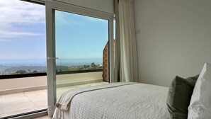 Ein Schlafzimmer mit einer großen Schiebeglastür, die auf einen Balkon mit Blick auf die Landschaft führt.