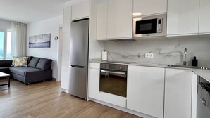 Eine moderne Küche mit weißen Schränken, einer eingebauten Mikrowelle und einem Edelstahl-Kühlschrank.