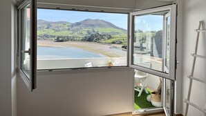 Een kamer met een groot raam, met uitzicht op een meer en heuvels.