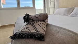 Een slaapkamer met een bed, een raam en uitzicht op de lucht.