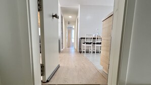 A hallway with a welcome mat, a dining area with chairs, and a kitchen area with cabinets. - Cozy apartmet in Hoznayo (Entrambasaguas)