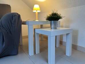 Simple, serene space with a white table, green plant, and soft lamp.