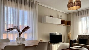 Una sala de estar moderna con comedor, televisor de pantalla plana y sofá.
