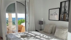 A bedroom with a large bed, a nightstand, a lamp, and a framed picture on the wall. - 2-Bed Sea View Apt, 10 mins from Puerto Banus (Nueva Andalucia)