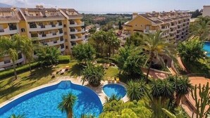 A resort with multiple swimming pools surrounded by lush greenery and palm trees. - 2-Bed Sea View Apt, 10 mins from Puerto Banus (Nueva Andalucia)
