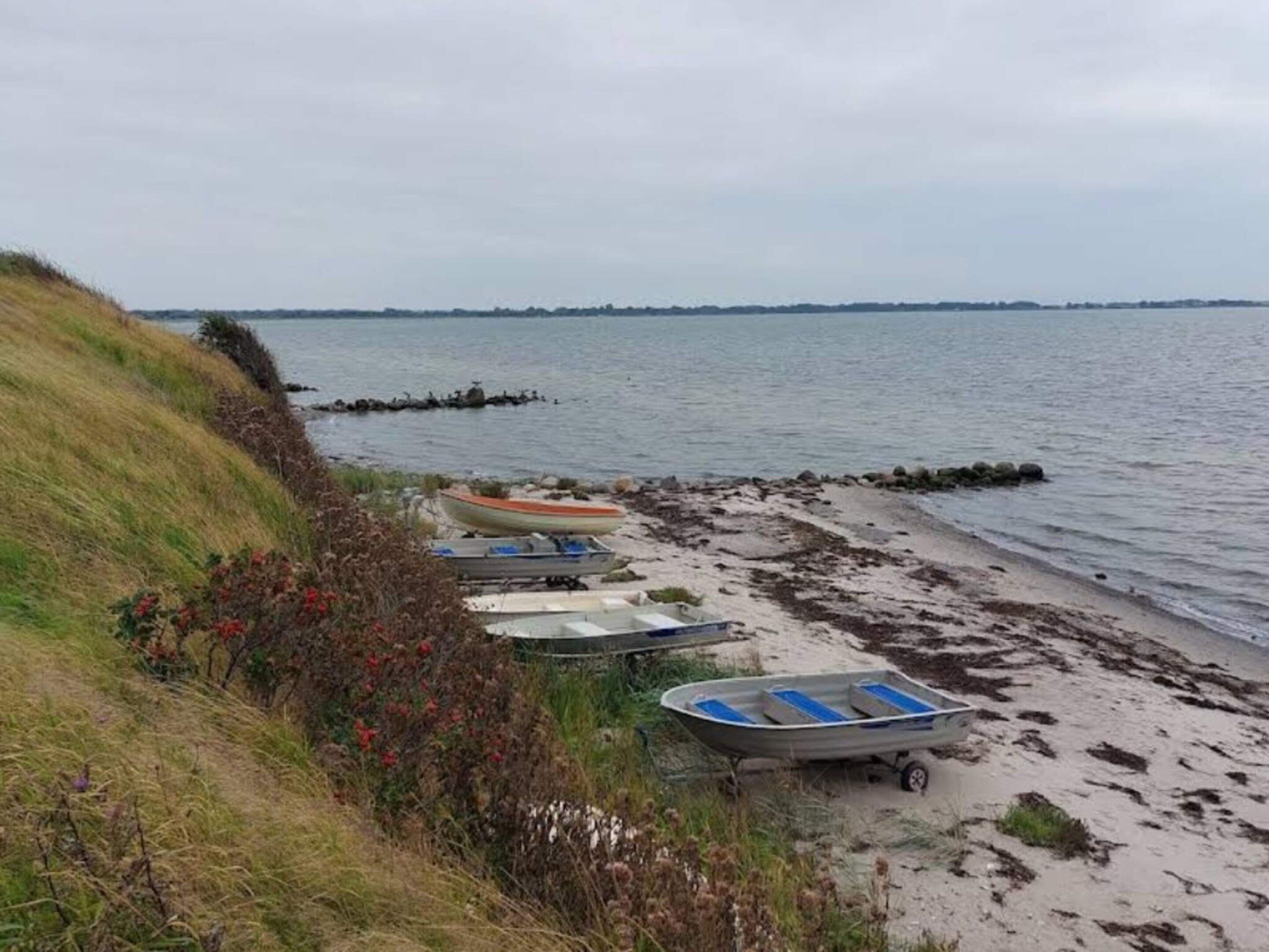 A beach with several small boats parked on the sand near the water.