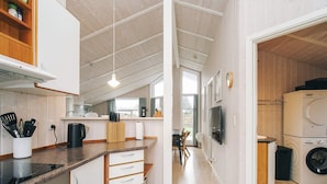 A modern kitchen with a central island, built-in appliances, and a dining area with a view. - 4 Star Holiday Home in Korsor (Korsor)