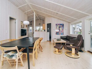 A spacious living area with a dining table, chairs, a sofa, and a television.