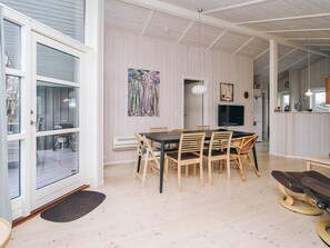 Un espace repas comprenant une table et des chaises, un téléviseur et des œuvres d’art accrochées au mur.