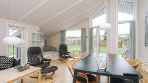 A spacious room with a large dining table, leather chairs, and a comfortable seating area with a sofa and chairs. - 4 Star Holiday Home in Korsor (Korsor)