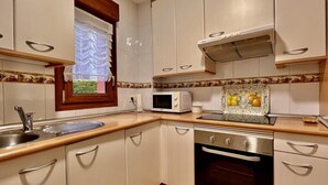 Una cucina compatta con mobili bianchi, un forno a microonde, un fornello e una lavastoviglie.