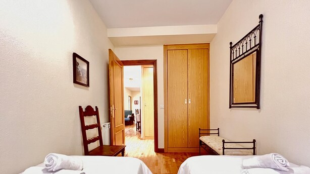 Camera d'albergo con due letti, un armadio in legno, un tavolino e una sedia.