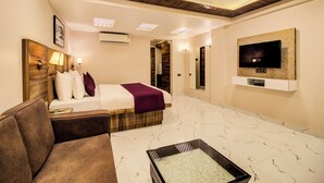 Une chambre d’hôtel comprenant un lit, un téléviseur fixé au mur, un coin salon et une petite table agrémentée d’un objet décoratif.