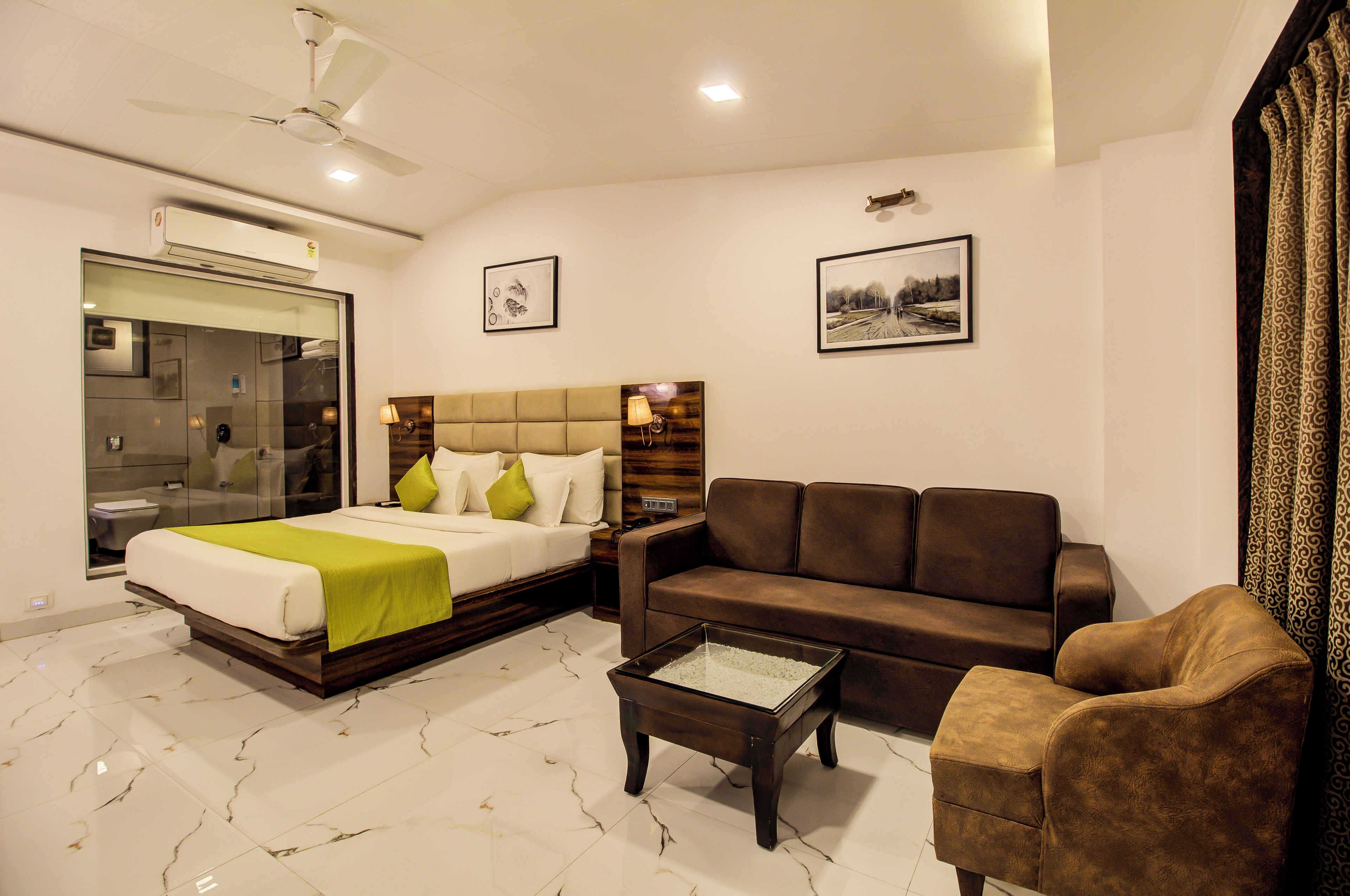 Una habitación de hotel moderna con cama, sofá, mesa de centro y televisor.