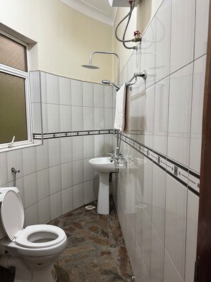 A small bathroom with a toilet, sink, and shower.