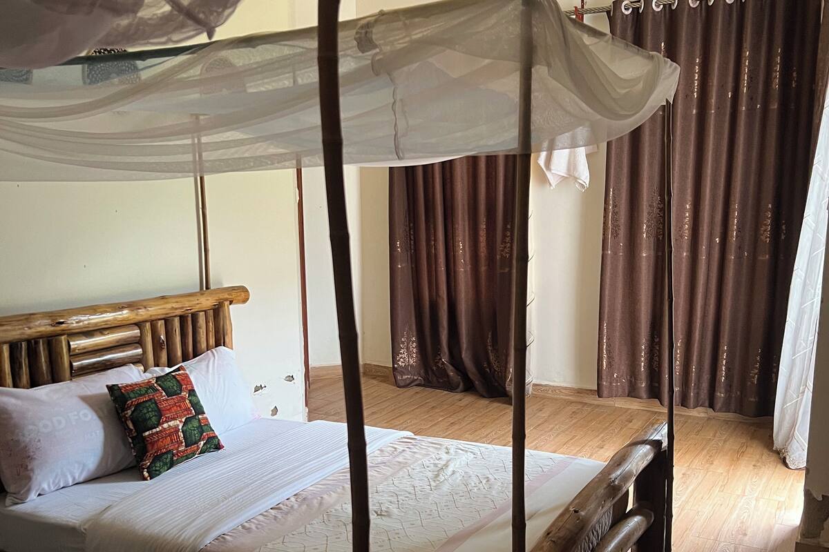 A four-poster bed with a canopy, wooden headboard, and a decorative pillow.