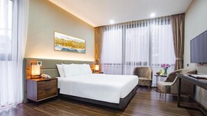 Una habitación de hotel con una cama grande, un escritorio, una silla, una mesita de noche y un televisor.