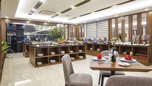 Una cocina moderna con una isla central, estantes de madera y un comedor con mesa y sillas.