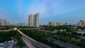 Un paisaje urbano con rascacielos, una autopista y zonas verdes.