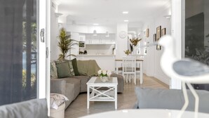 A modern living room with a grey sofa, a white coffee table, and a dining area with a white table and chairs.
