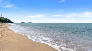 A beach with calm waves, a sandy shore, and distant islands.