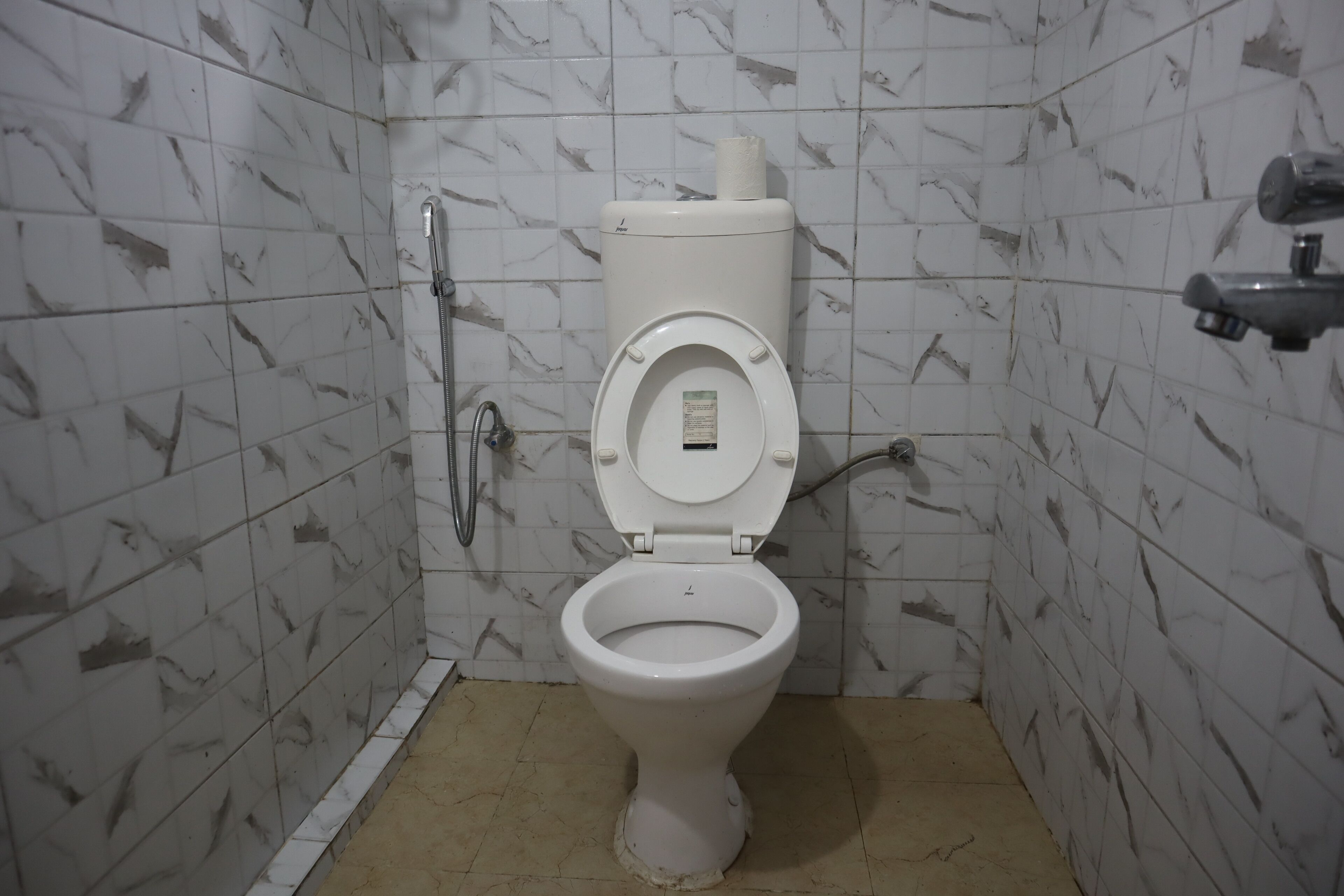 A bathroom with a toilet, a shower, and a hand dryer.