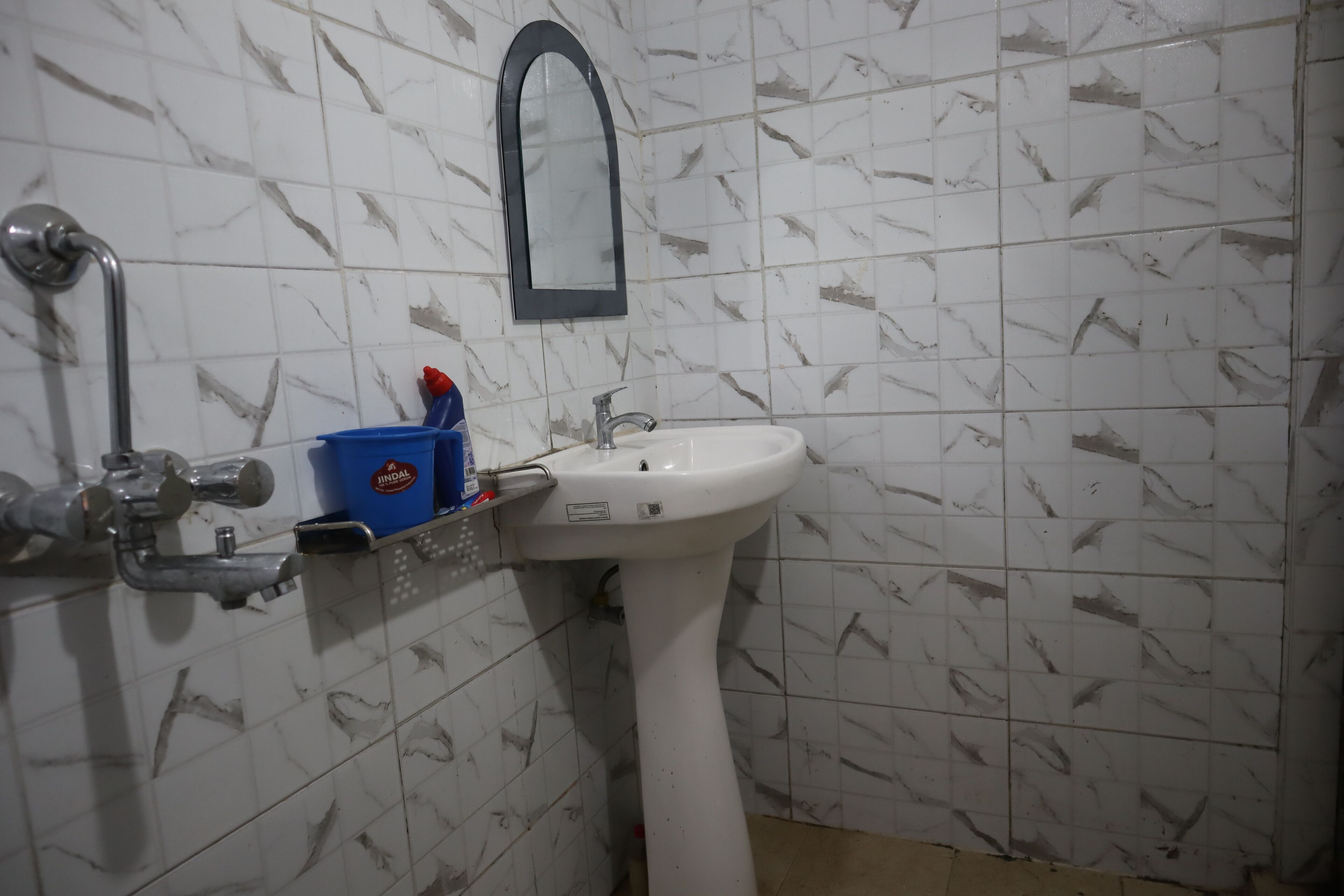Un baño con un lavamanos blanco, un espejo y un dispensador de jabón azul.