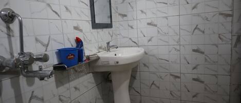 Un baño con un lavamanos blanco, un espejo y un dispensador de jabón azul.