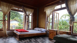 Een houten kamer met een bed, een tafeltje en een raam met gordijnen.