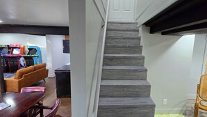 A staircase with a modern design, leading to a room with a dining area featuring a wooden table and chairs. - The Green House! Sleeps 12 (Trenton)