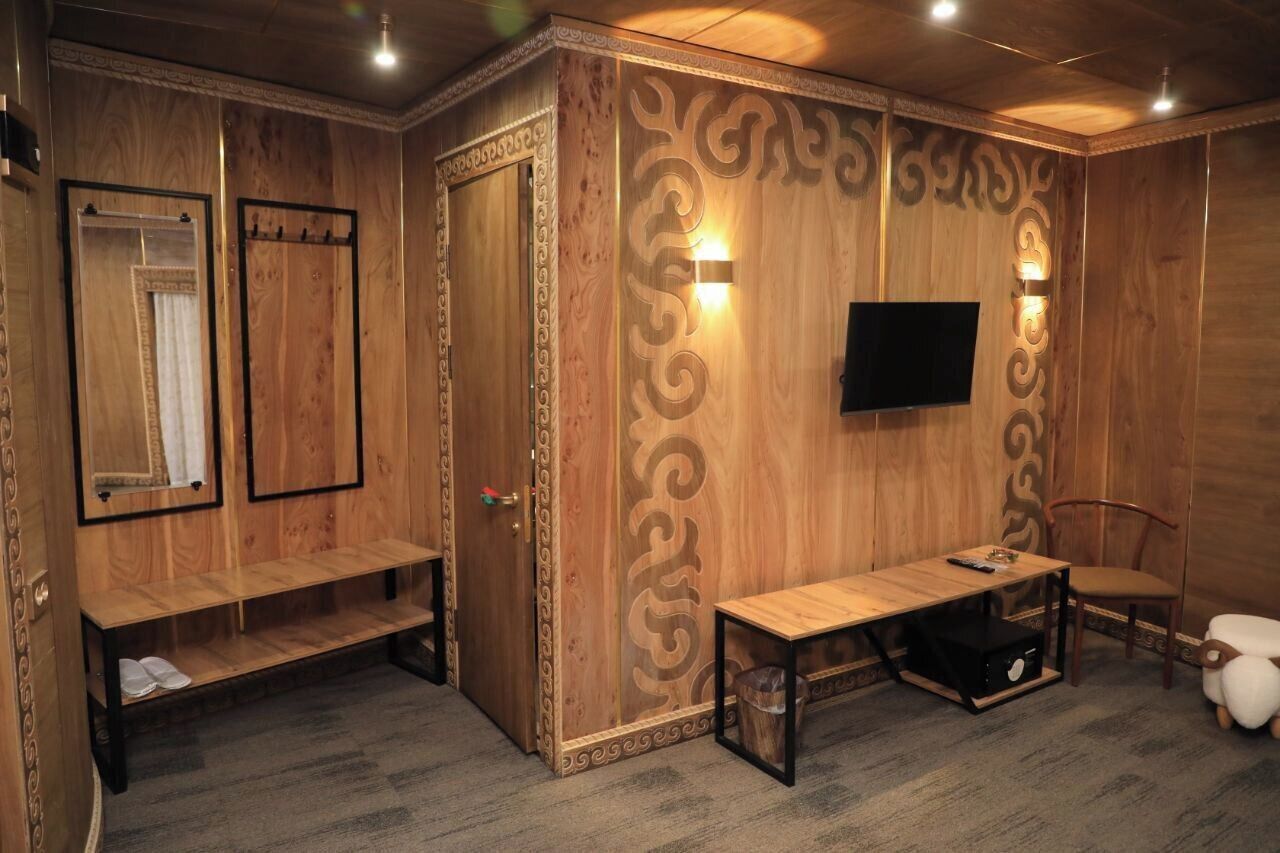 A wooden room with a bench, a table, a TV, and a chair.