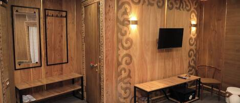 A wooden room with a bench, a table, a TV, and a chair.