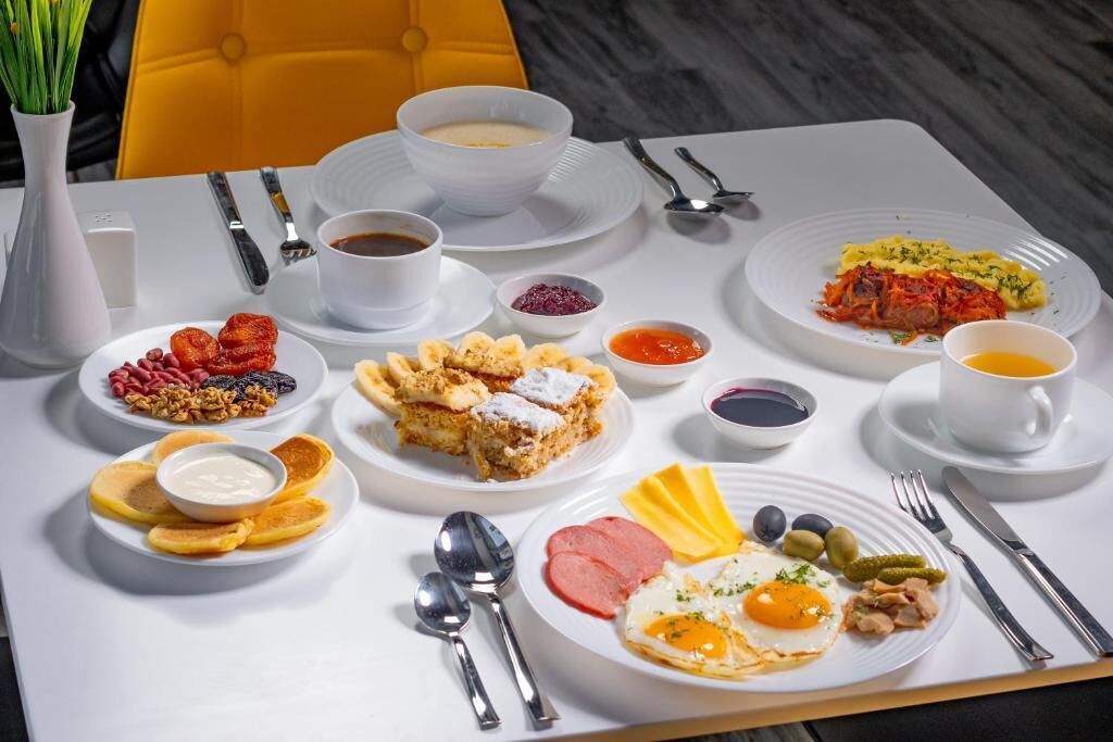 A breakfast buffet with various dishes including eggs, meats, fruits, and pastries.