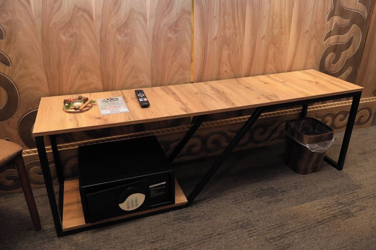 A wooden desk with a remote control and a small decorative item on it.