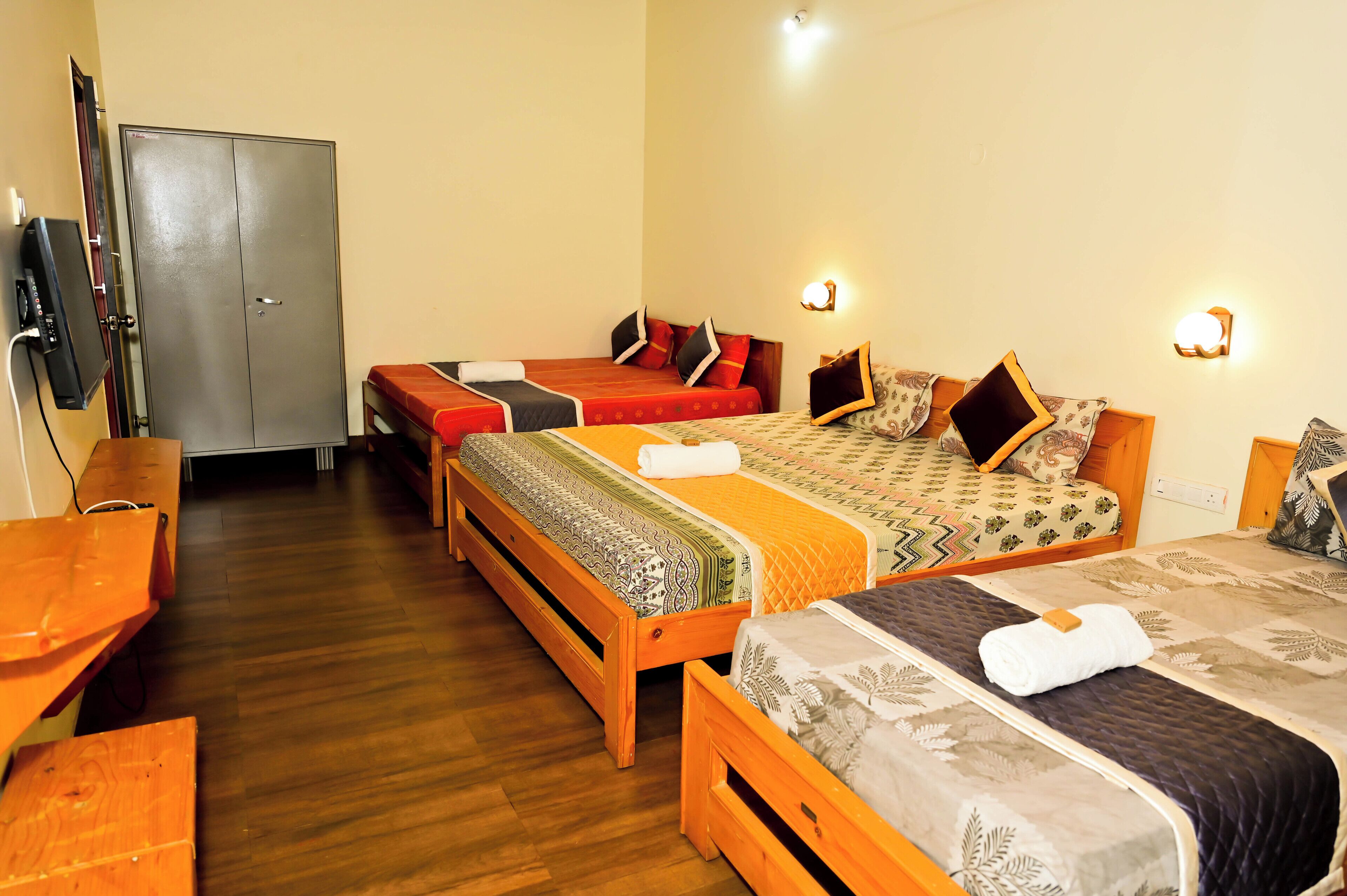 Habitación de hotel con tres camas de madera, un armario y un escritorio.