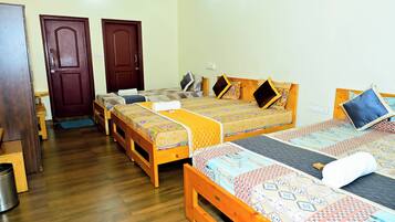 Una habitación con cuatro camas de madera, cada una con ropa de cama y almohadas estampadas. Hay dos puertas de madera y un banco de madera.