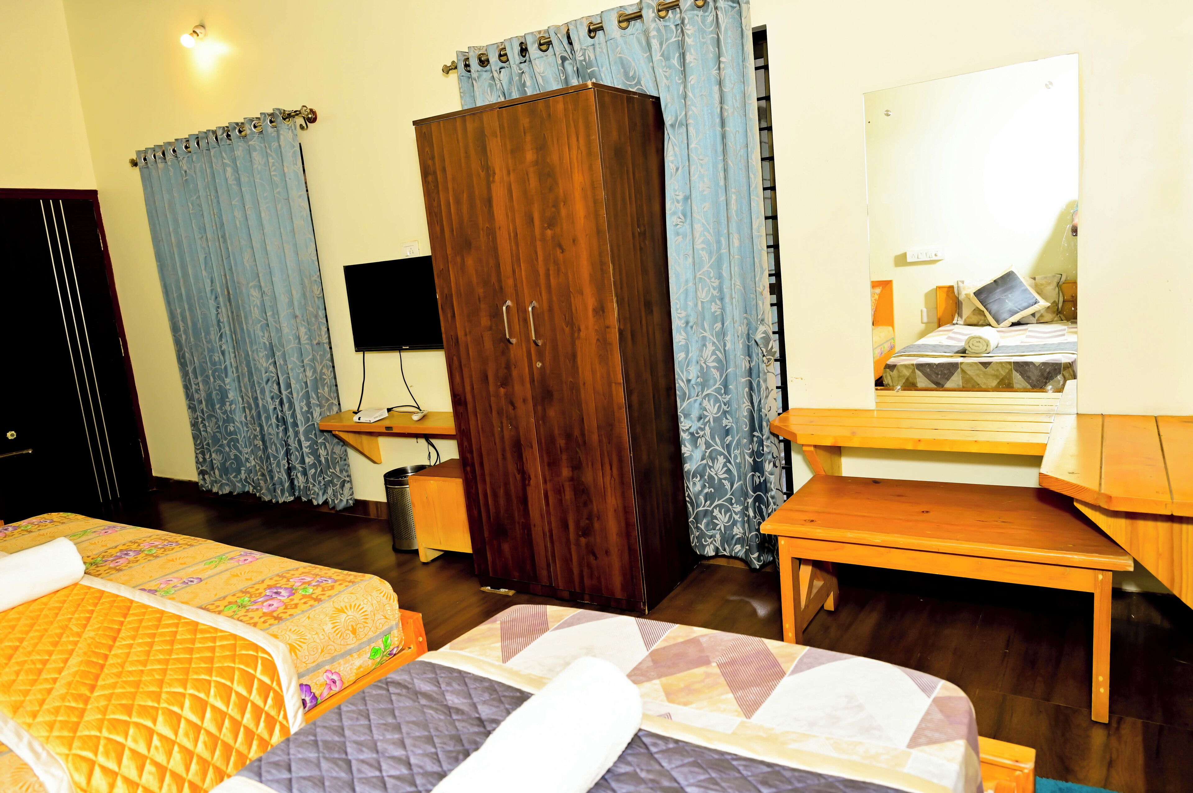 Habitación de hotel con dos camas, un armario, un escritorio y un espejo.