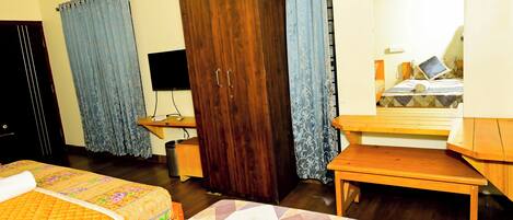 Habitación de hotel con dos camas, un armario, un escritorio y un espejo.