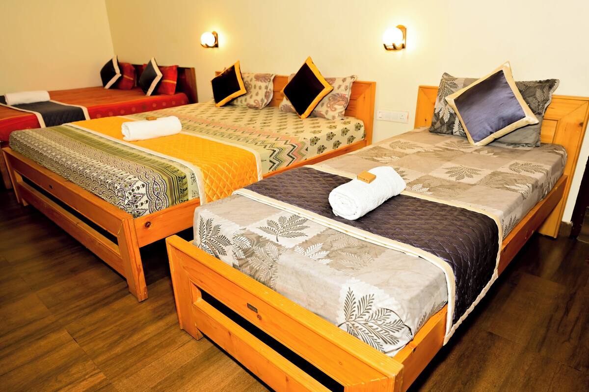 A hotel room with three wooden beds, each with a distinct patterned bedspread.